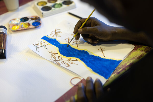 Omar, exilé soudanais, dessine un "souvenir" de son pays natal.