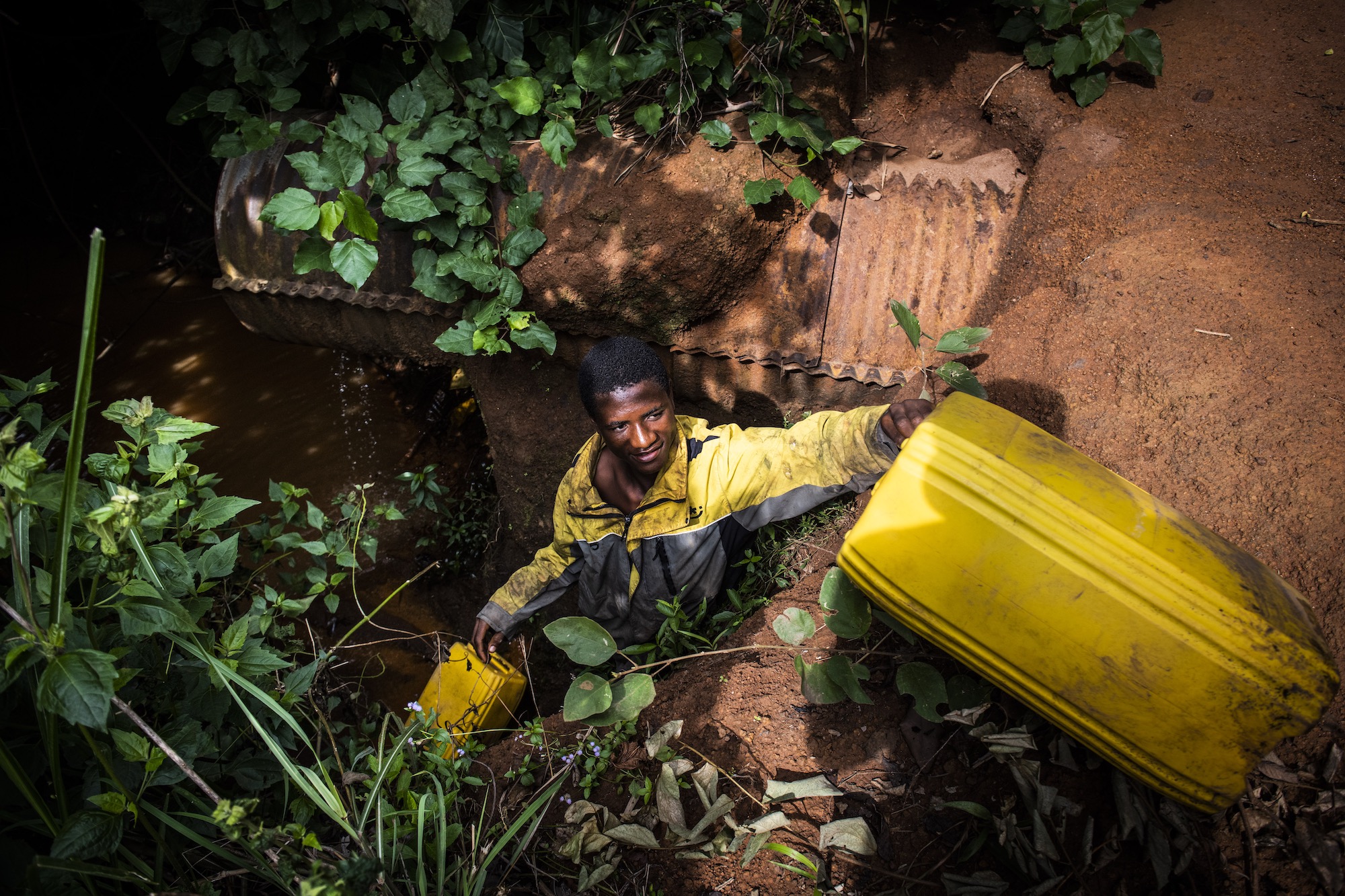 Doumbia, 16 ans, remplit des jerricans d'eau pour fabriquer du pesticide pour les champs de son père.