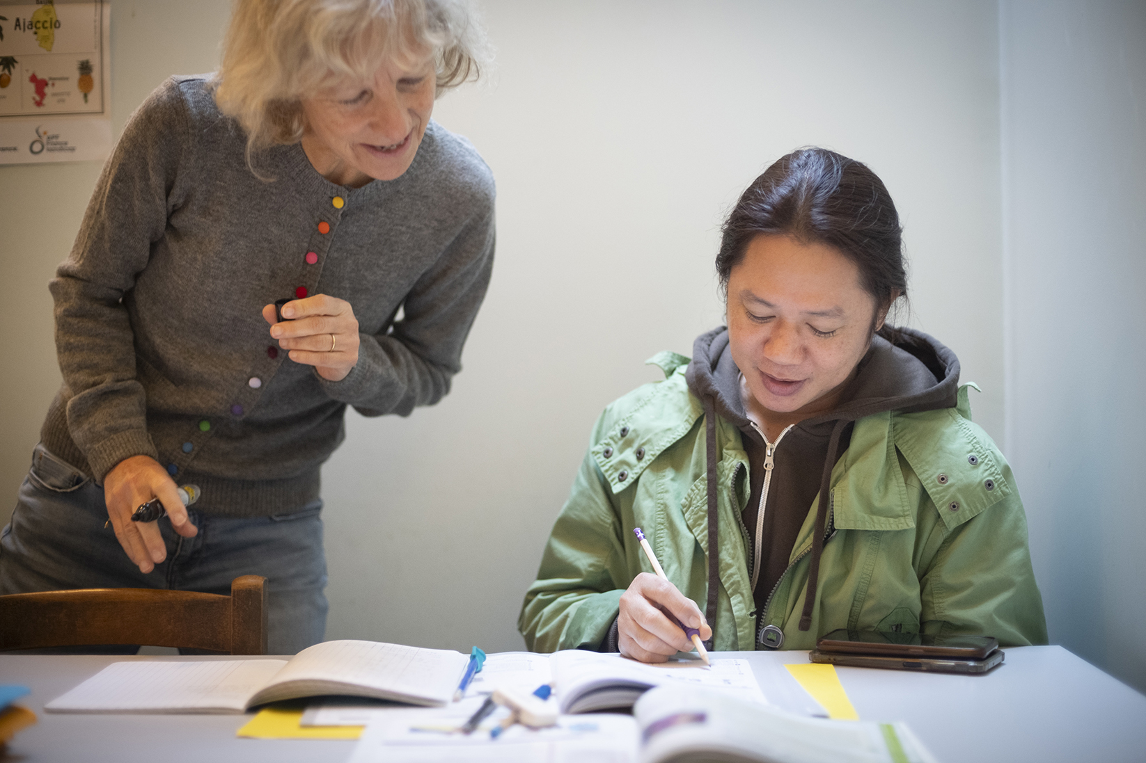 une bénévole du secours catholique avec une personne migrante apprenant le français