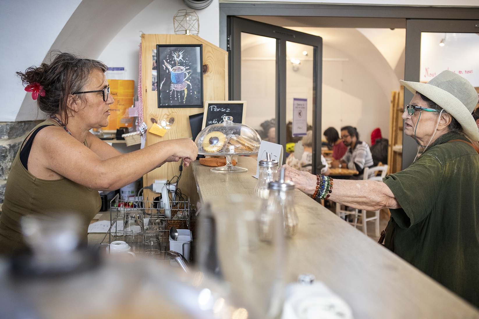 une bénévole sert une boisson derrière le comptoir du café solidaire anais à nimes