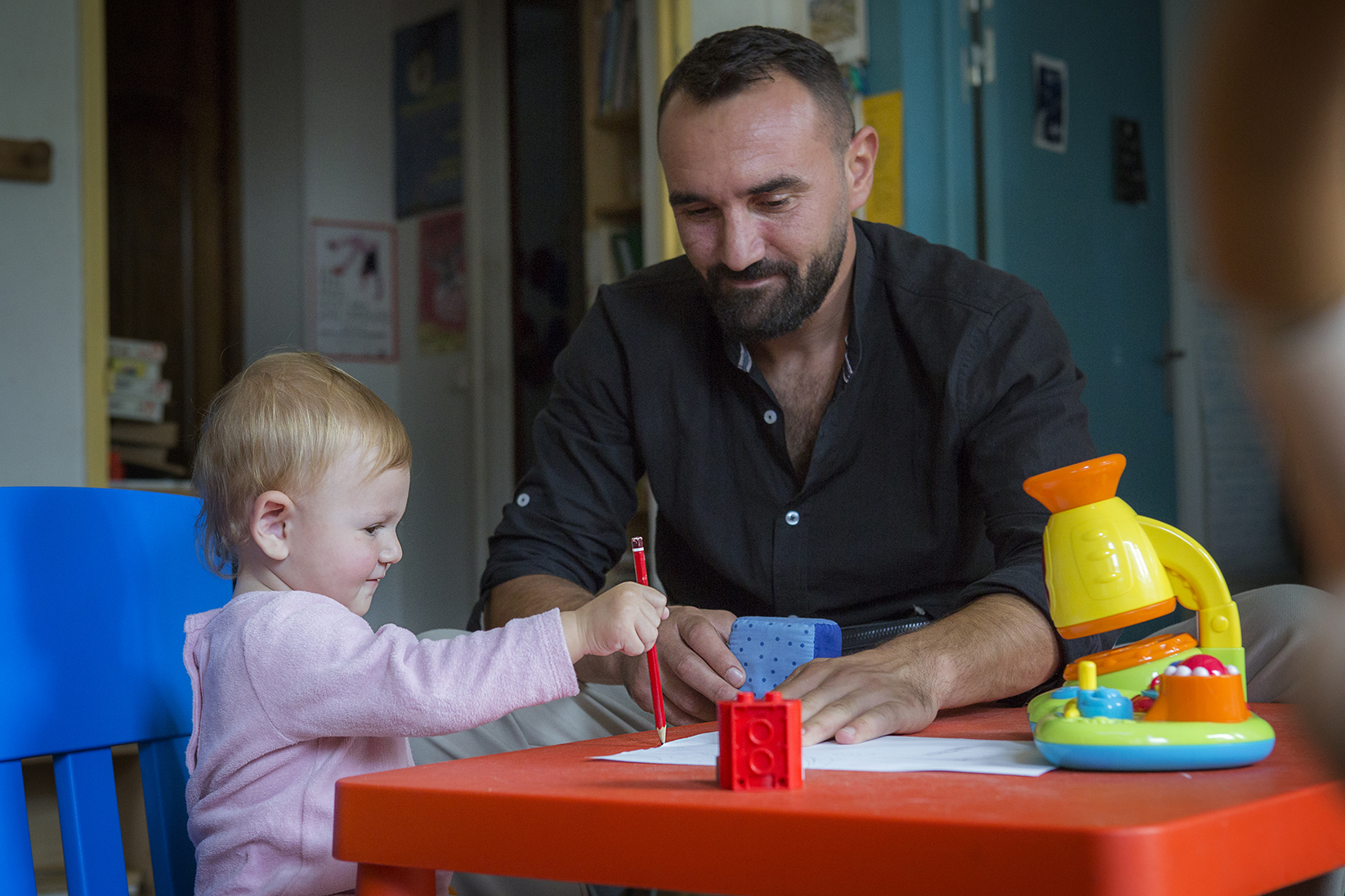 un père avec son enfant dessinent à la maison des familles