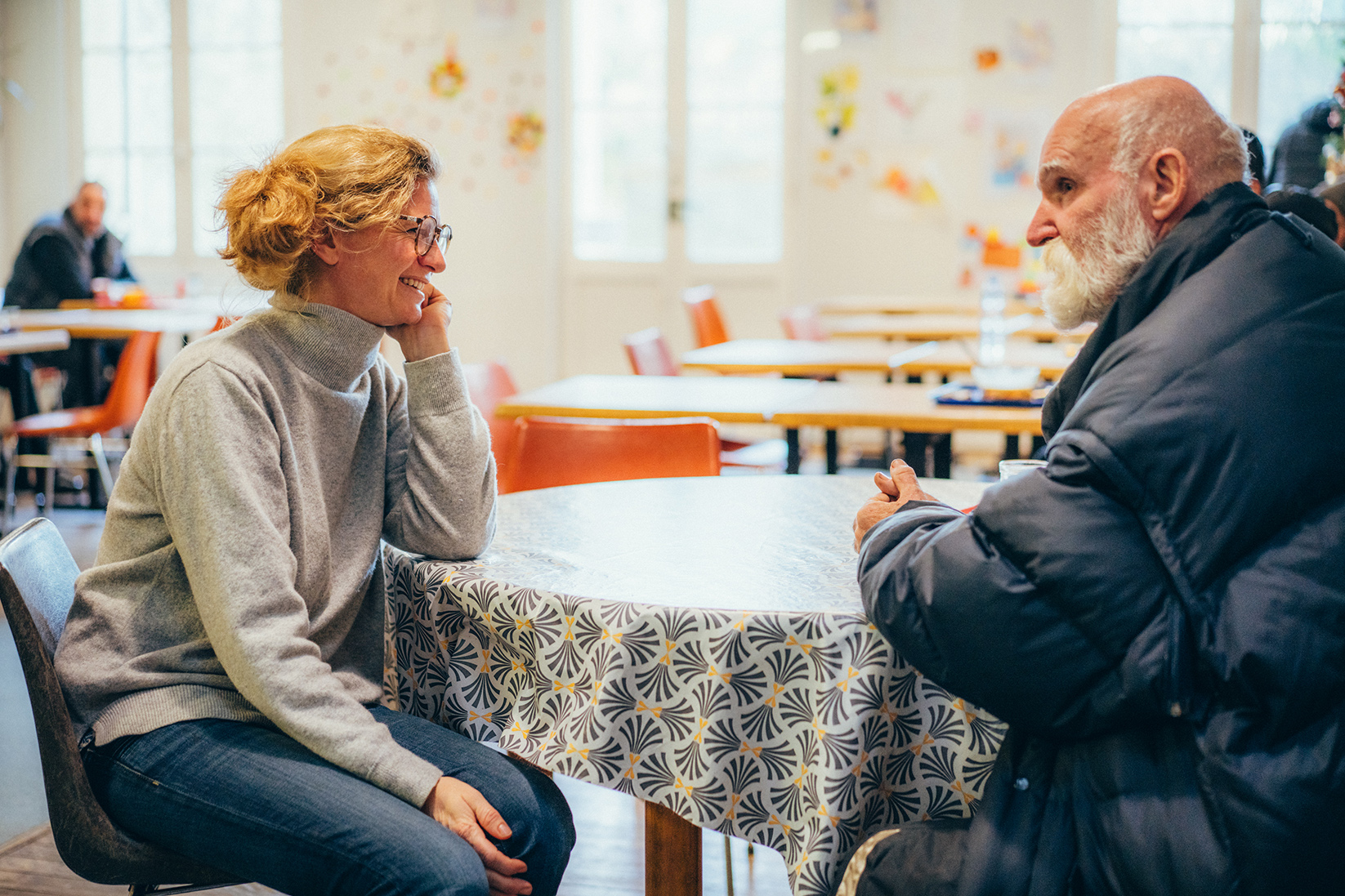 une bénévole et un accueilli assis à une table