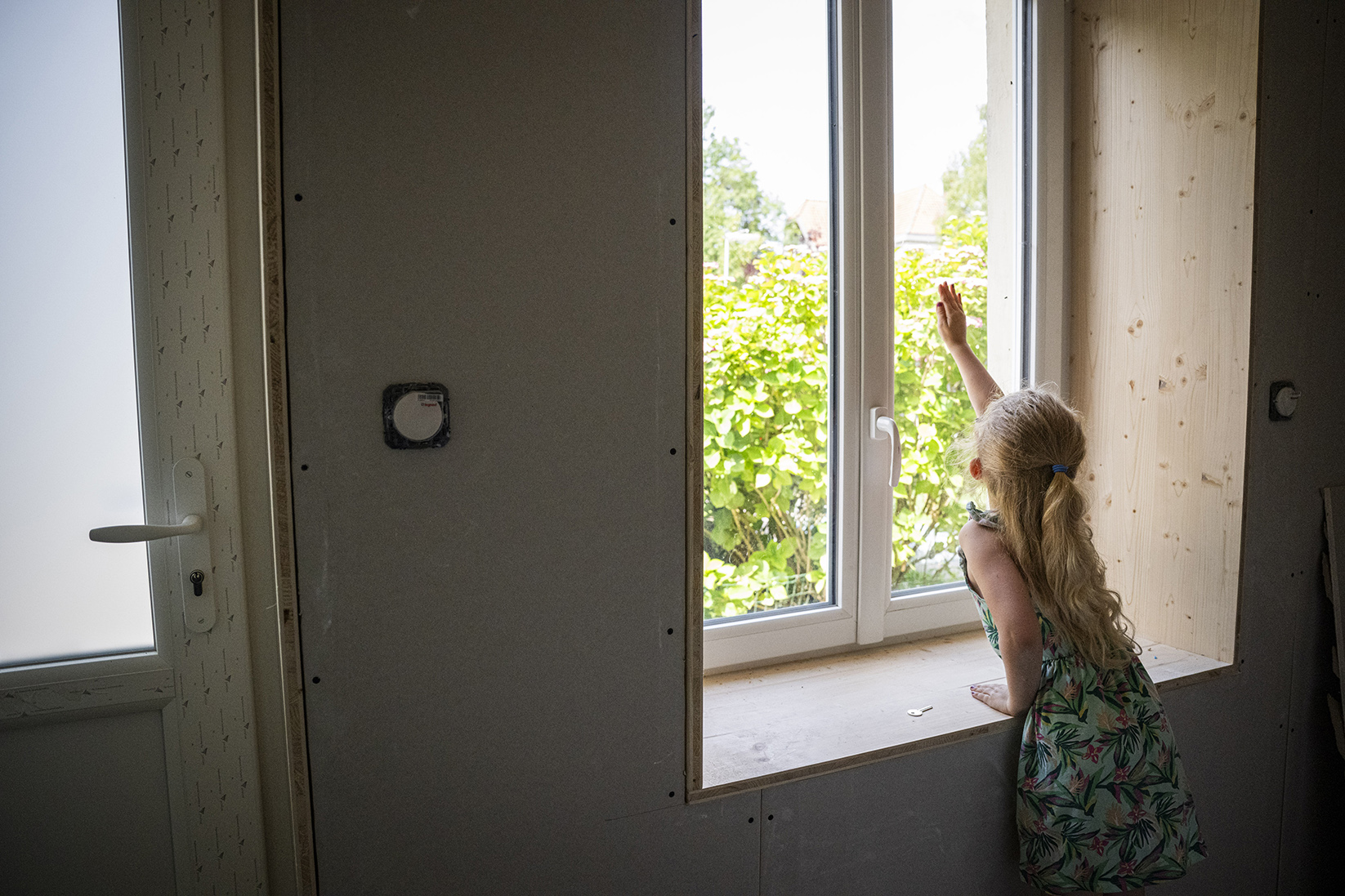 une petite fille touche une fenêtre avec sa main 