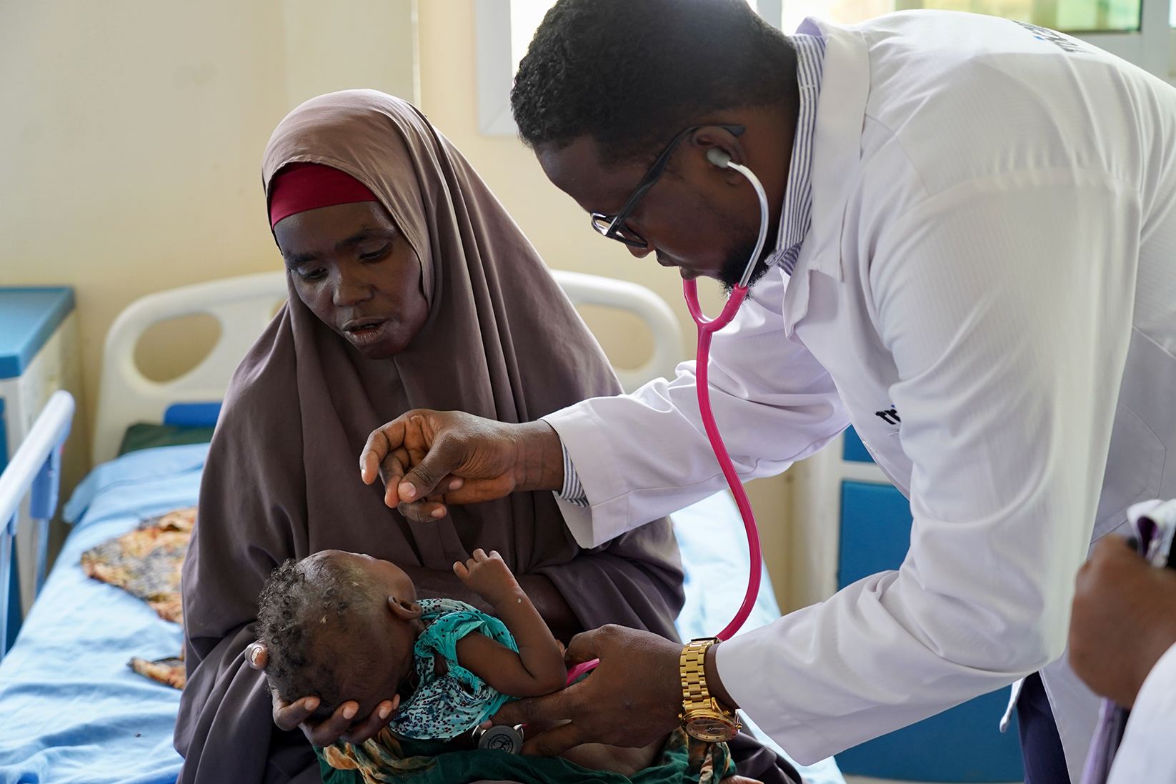 Un médecin penché sur un bébé dans les bras de sa mère