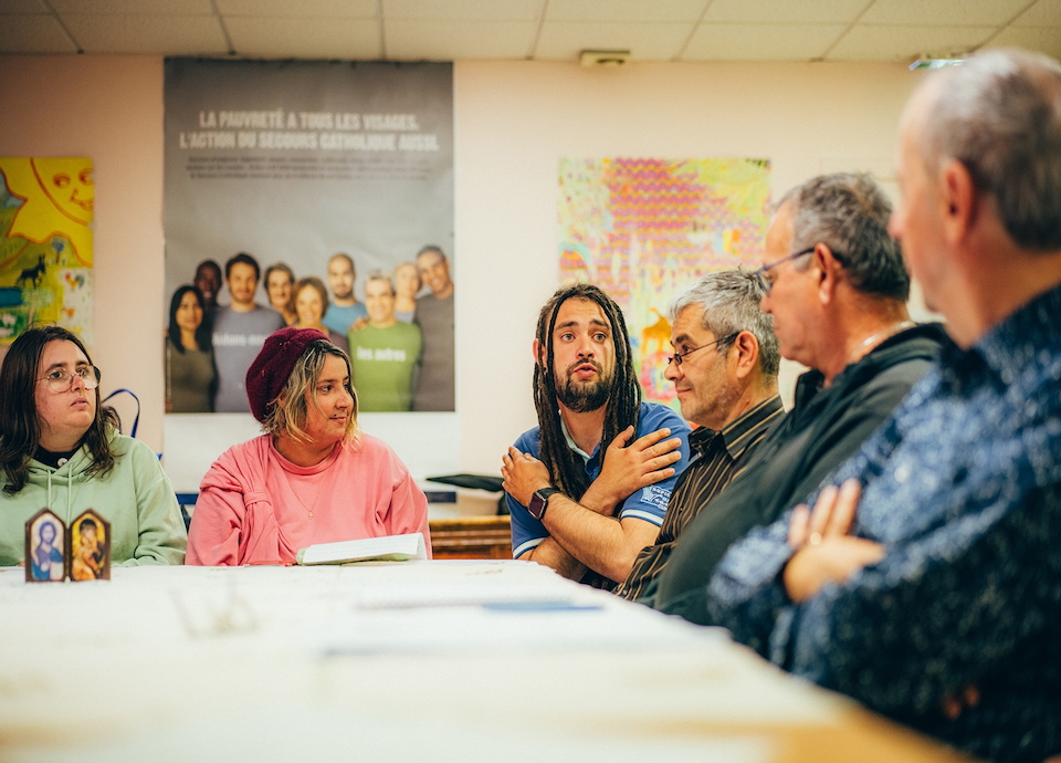 Des hommes et des femmes du groupe de partage d'Evangile du Secours Catholique de Brive sont réunis autour d'une table. Ils écoutent un des participants.