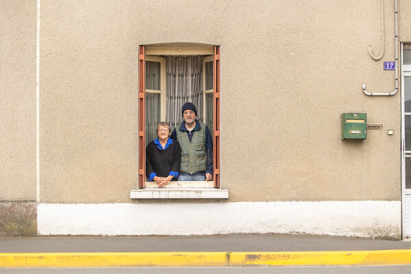 Bernadette et Jacques, à la fenêtre de leur maison, sur la rue.