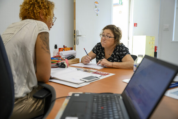 Échange entre une personne hébergée et l'animatrice autour d'un bureau.