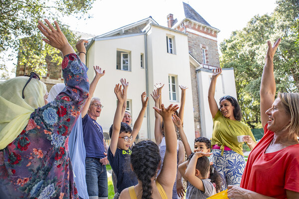 un groupe de personnes lèvent les bras au ciel dans le jardin de la villa