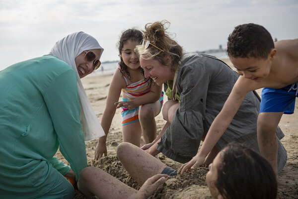 deux femmes et trois enfants jouent sur la plage