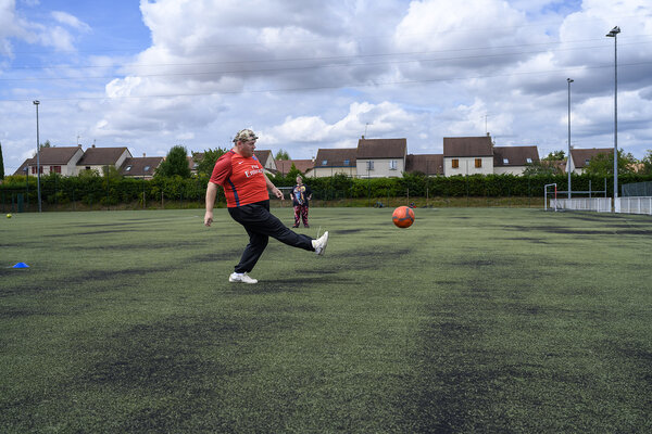 Un homme joue au ballon sur un terrain de foot.