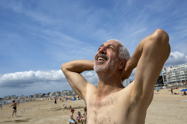 un homme à l'air heureux regarde le ciel bleu debout sur la plage