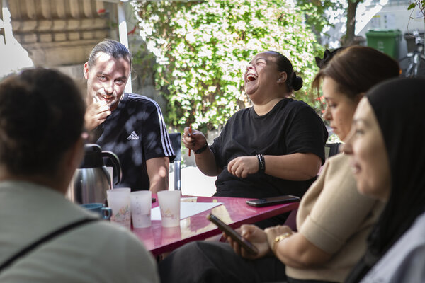 une femme rit aux éclats entourée d'autres parents à la Maison des familles