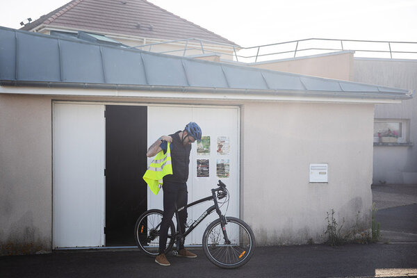 Un travailleur en situation de handicap quitte le foyer d'hébergement à vélo.