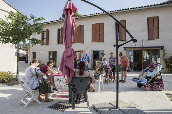 Des habitants prennent le café sur la place, au centre du Hameau.