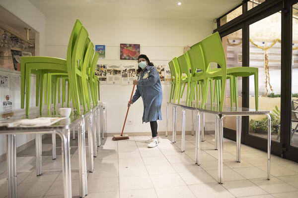 Une bénévole balaie la salle de restauration.