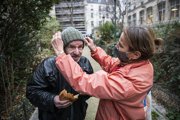  Marie-Anne donne à Jean-Philippe un bonnet tricoté par une personne accueillie au Secours Catholique.