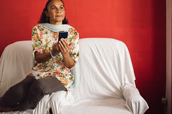 Monique sur son canapé tient un smartphone