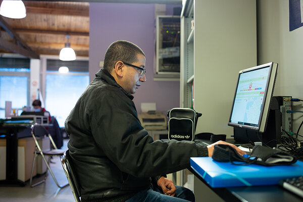 Un homme devant un ordinateur, dans une permanence d'aide.