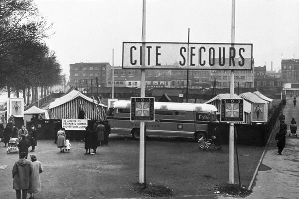 La Cité Secours de Porte d'Orléans créée en 1954 pour répondre au grand froid qui touche le pays cette année là. Elle sera le premier des lieux d'accueil pour les personnes vivant à la rue que le Secours Catholique va développer par la suite.