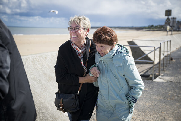 deux personnes marchent sur la plage en se tenant par le bras