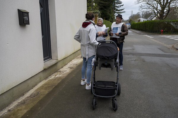 deux bénévoles discutent dans la rue avec une femme qui tient une poussette