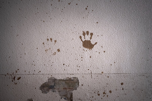 Traces de mains boueuses sur un mur.
