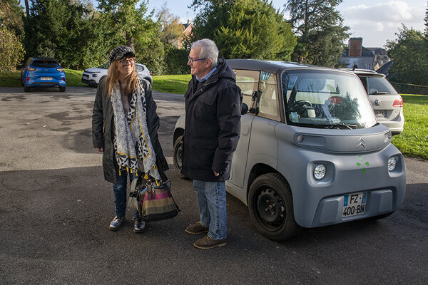 Un bénévole et un usager à côté d'un voiture électrique.