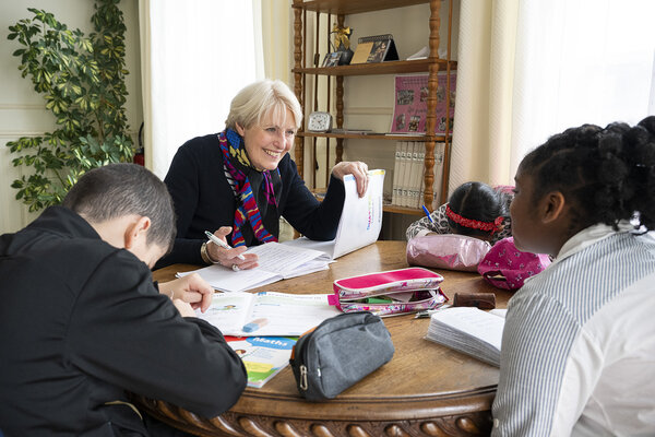 Marie-France attablée avec les enfants pour suivre leurs devoirs