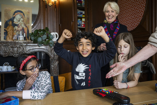 enfant heureux levant les bras, entouré de deux petites filles et d'une bénévole