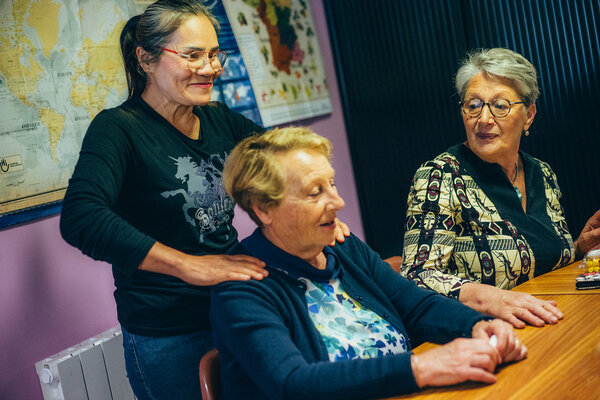 Une femme masse les épaules d’une autre femme en attendant le repas. 