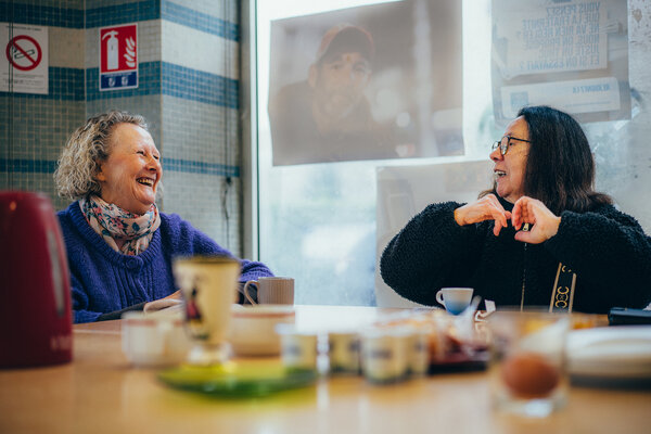 deux femmes bavardent en riant autour d'un café