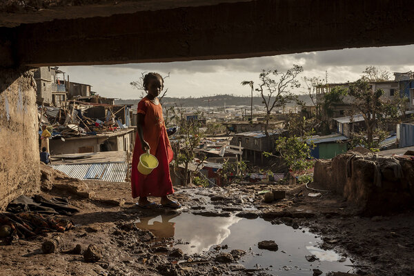 après le cyclone, une enfant avec un seau, dans un paysage dévasté