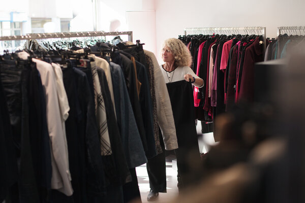 Fabienne, la vendeuse, réorganise les portants de vêtements.