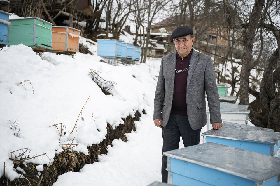 Un homme pose à côté de ses ruches