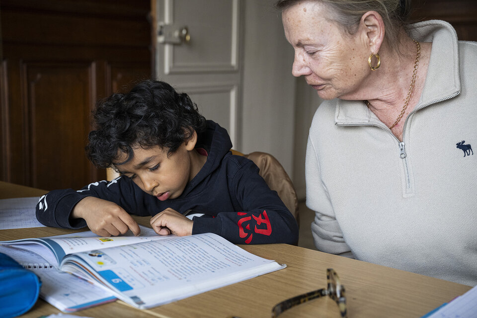 Une bénévole du Secours Catholique aide un enfant à faire ses devoirs