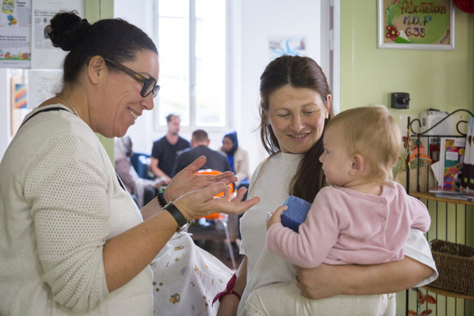 Une femme sourit à une enfant et sa mère 