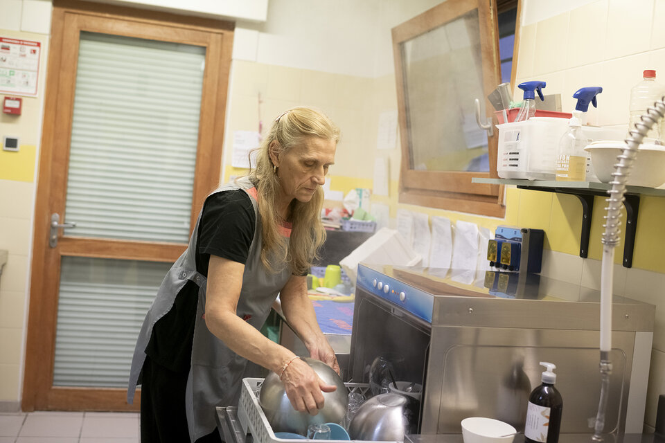une femme, travailleuse pauvre, range de la vaisselle 