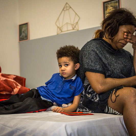 Justine et son fils, sur le lit de la chambre d'hôtel où ils vivent.